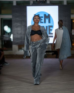 Model showcases grey velvet loungewear ensemble on runway with illuminated backdrop.