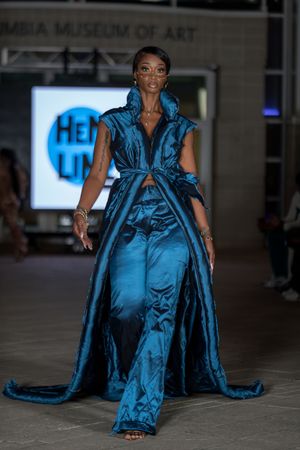Dramatic teal satin ensemble with matching wide-leg pants displayed on fashion runway.