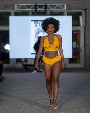 Fashion model walks runway wearing yellow swimwear during fashion show at Columbia Museum of Art.