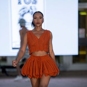 Burnt orange crochet dress with peplum detail displayed during fashion show catwalk presentation.