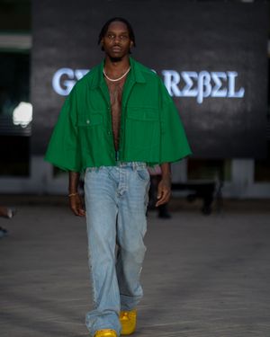 Bright green jacket paired with light wash denim jeans and yellow shoes on fashion runway.