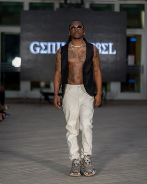 Fashion model walks runway in white pants and black vest at Columbia Museum of Art fashion show.