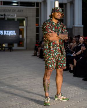 Models wearing floral print dresses walk the runway at a fashion show.