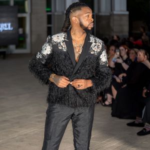 Fashion model presents black ensemble with dramatic feather details during runway show.