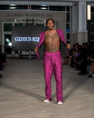 Model showcases vibrant pink pants with black top during fashion show at Columbia Museum of Art.