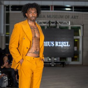 Bright yellow suit ensemble displayed on runway at Columbia Museum fashion show.
