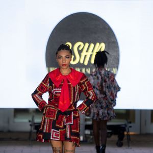 Bold red patterned outfit with geometric designs displayed on fashion runway.
