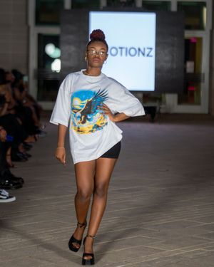 Fashion show features casual streetwear look with oversized white t-shirt on runway.