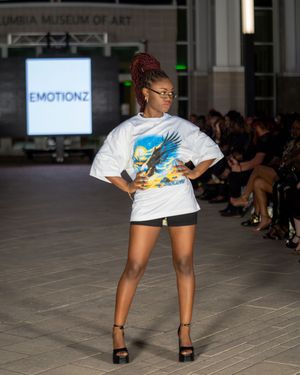Model showcases white graphic t-shirt and shorts during fashion show at Columbia Museum of Art.