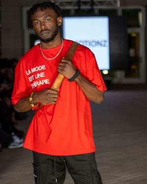 Bright red t-shirt styled with dark cargo pants on museum runway.
