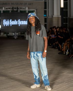 Model showcases casual denim and gray t-shirt combination on museum runway.