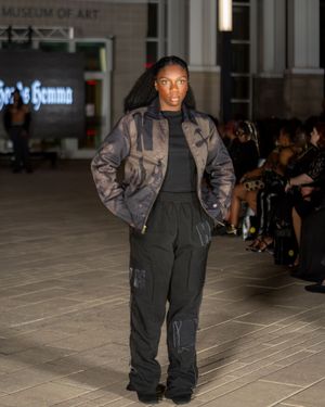 Oversized gray jacket paired with black cargo pants presented during fashion show.
