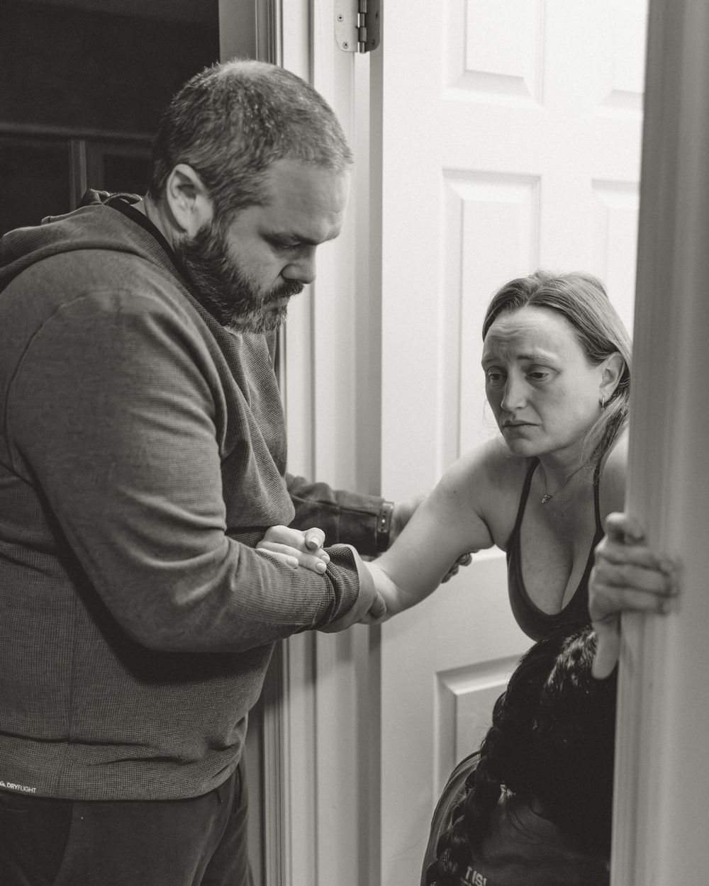 A sequence of four black and white photographs showing a person leaning against a doorframe in distress.