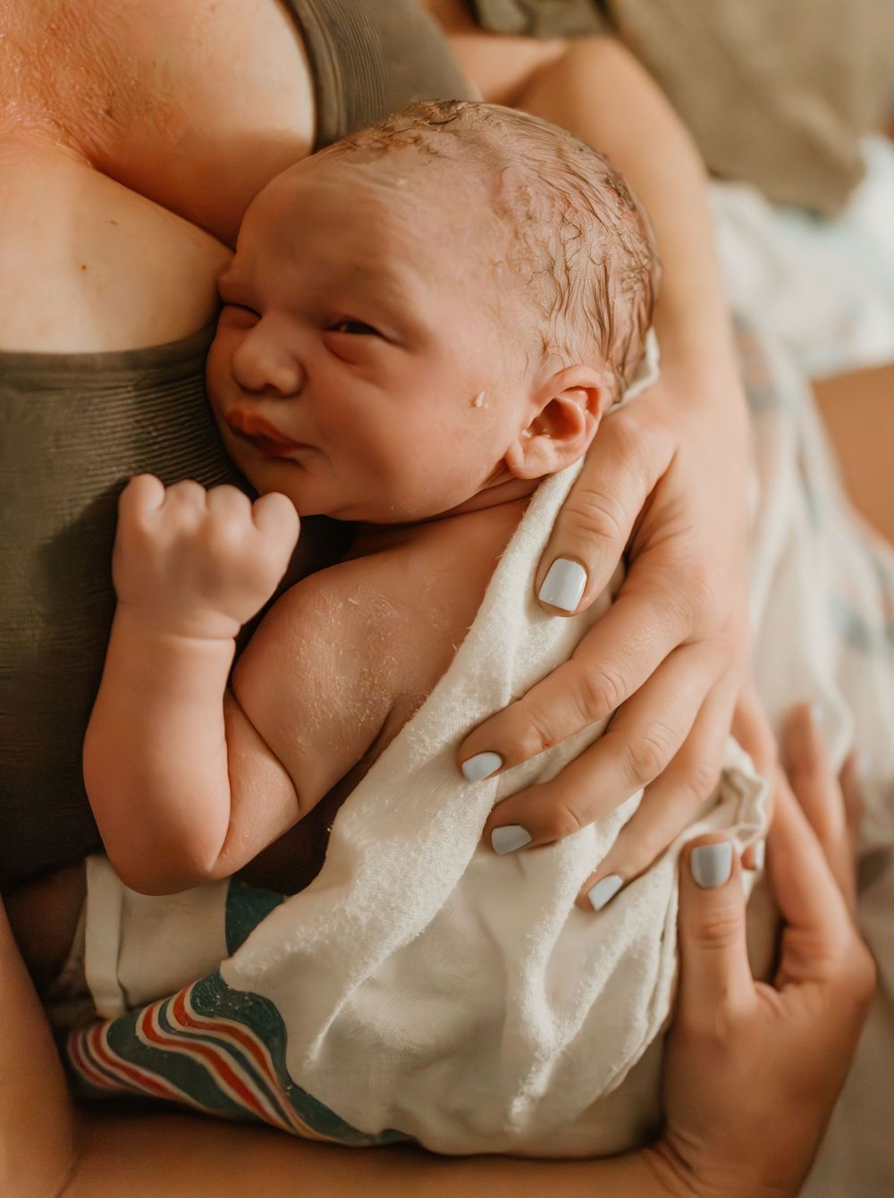 Close-up detail shots of a newborn baby's hands and fingers against white fabric.
