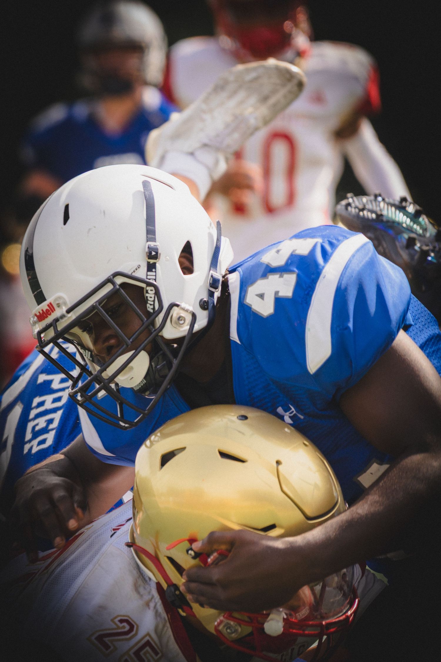 Close-up photo of football players wearing blue and white jerseys with gold helmets during a game.