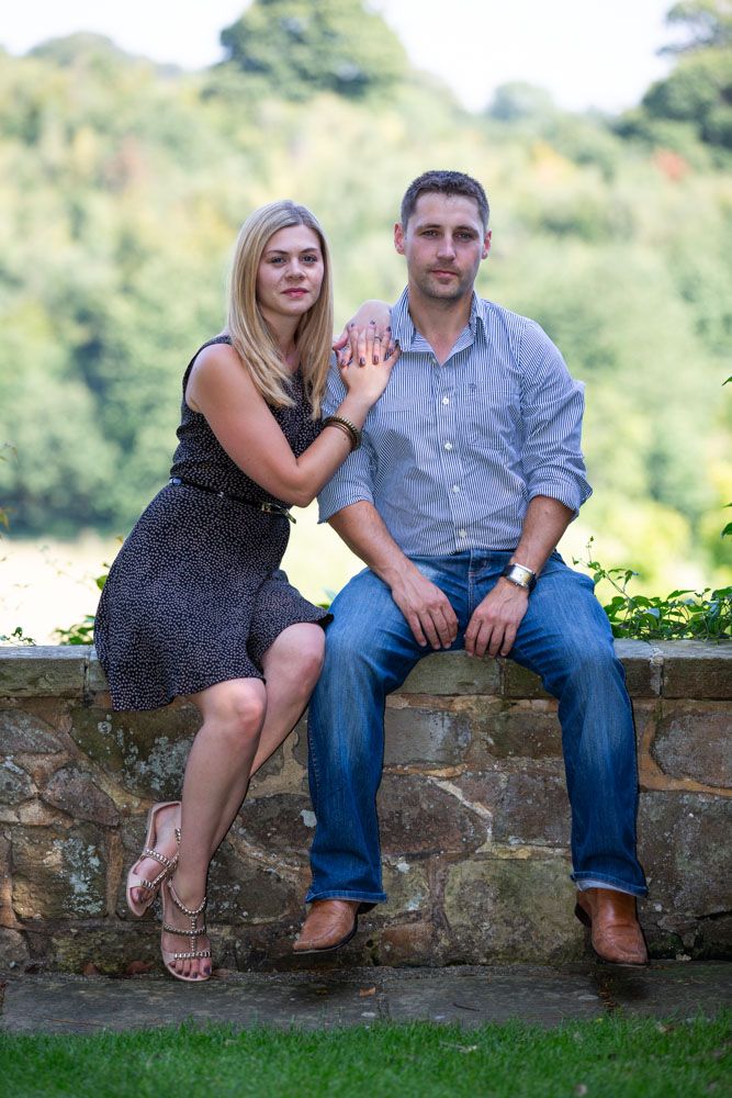 Couple sit on garden wall of country mansion