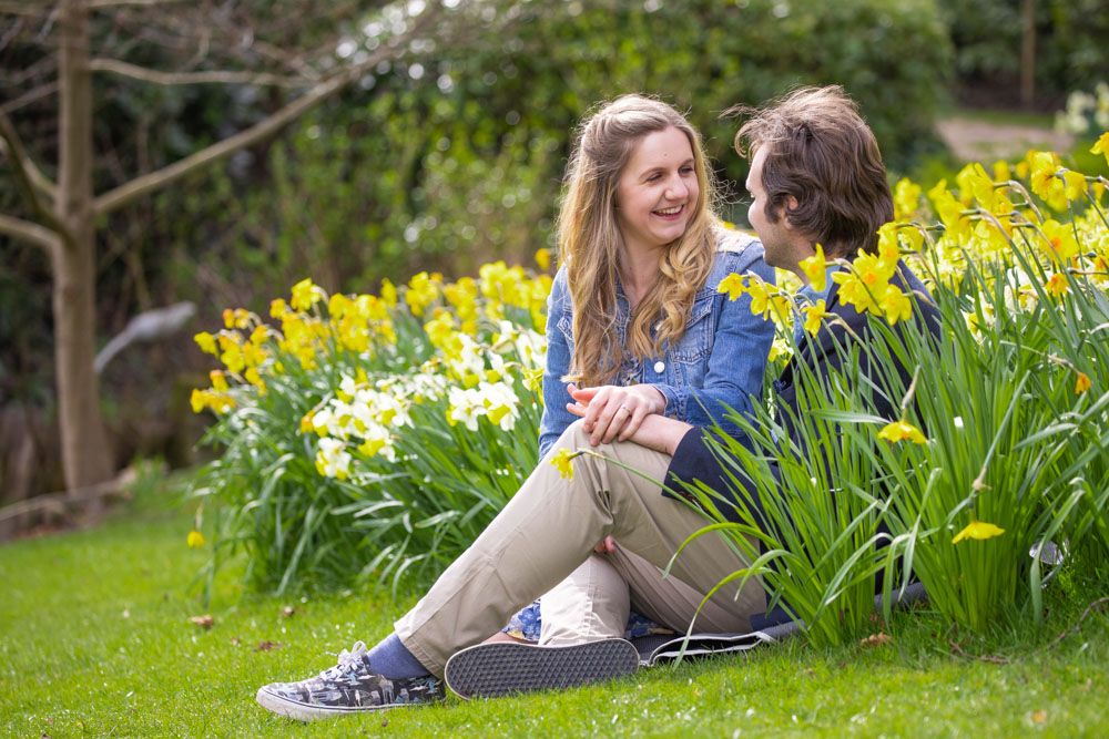 Couple site romantically in amongst daffodils in spring garden