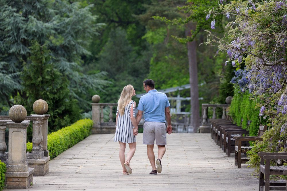 Couple walk along terrace of grand house garden