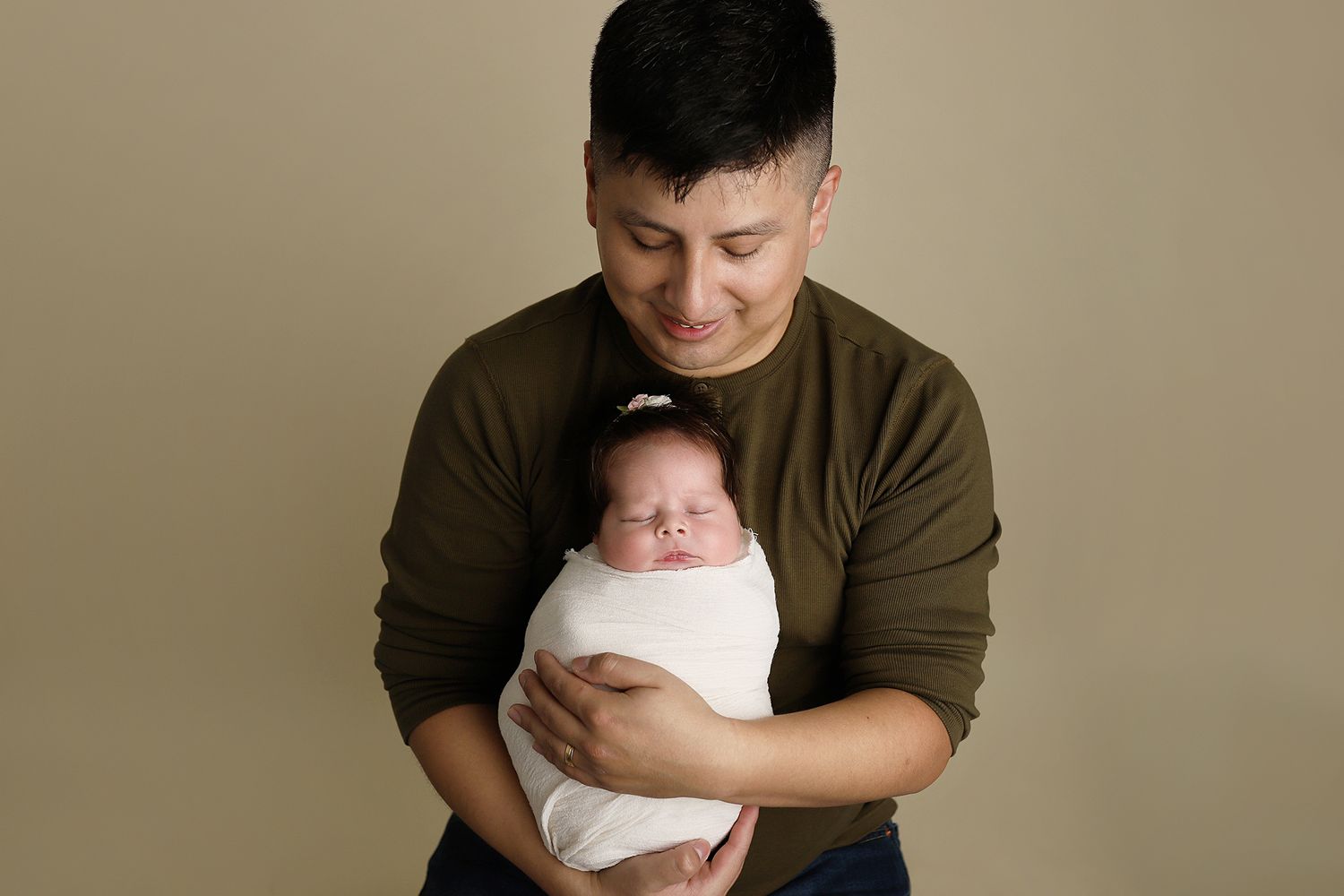A series of six tender newborn photography poses showing a baby wrapped in white fabric against a neutral backdrop.