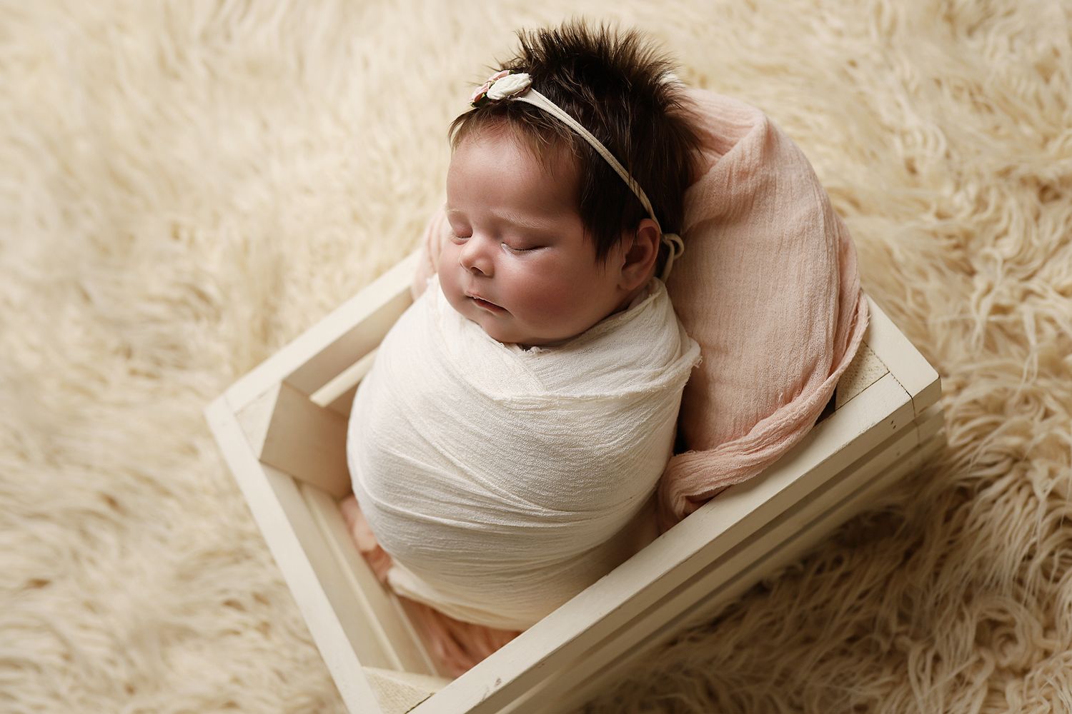 Collection of artistic newborn portraits showing baby swaddled in white against a beige furry background. Baby photography utah