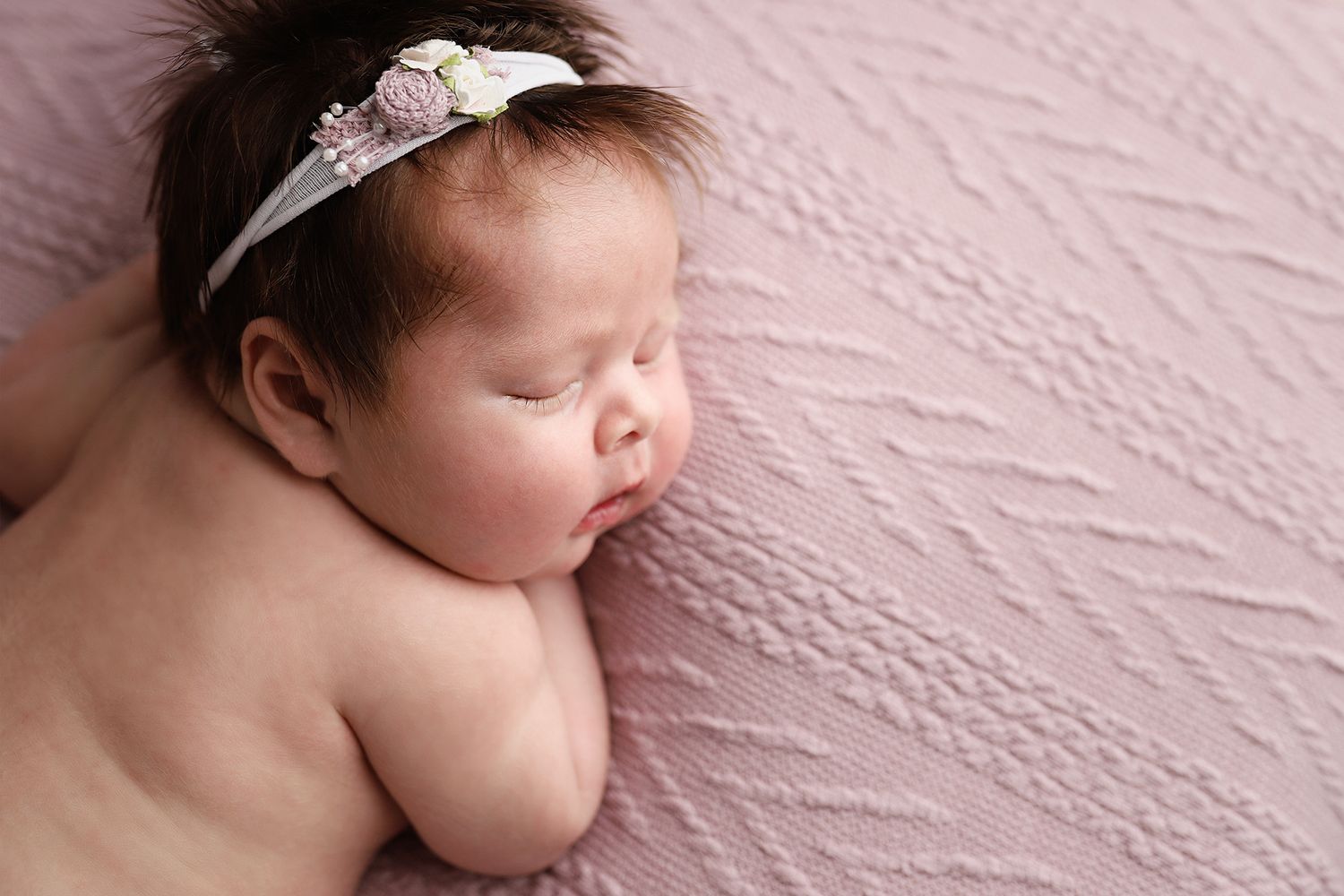 A series of peaceful newborn baby photos showing gentle sleeping poses against a soft pink textured background. Newborn photography utah