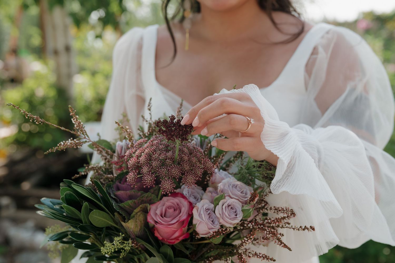 A wedding bouquet featuring pink roses and purple flowers with delicate white accents.