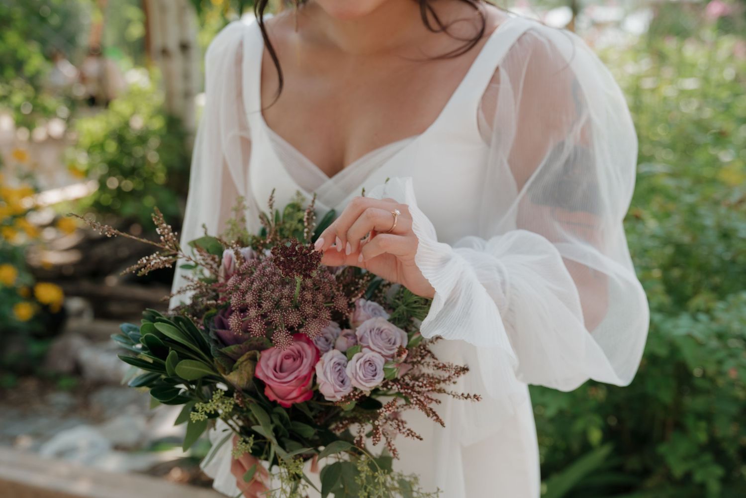 Close-up details of a romantic bridal bouquet featuring pink roses and purple wildflowers.