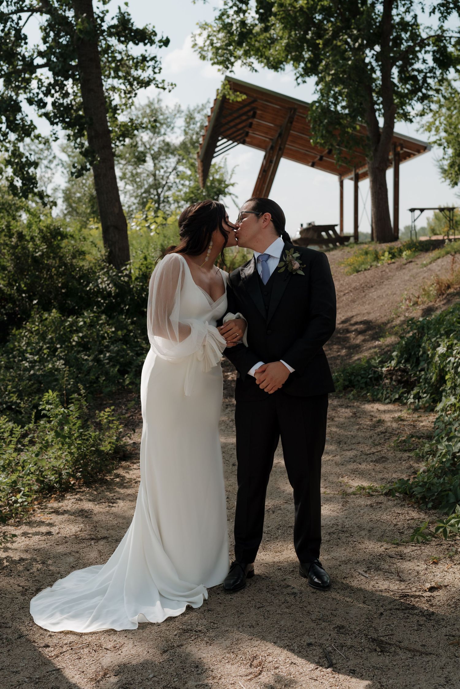 A series of romantic wedding photos showing a couple in white dress and black suit outdoors on a wooded path.