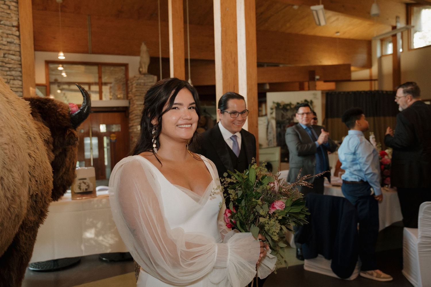 Rustic wooden reception venue with stone walls and exposed beams filled with wedding guests.