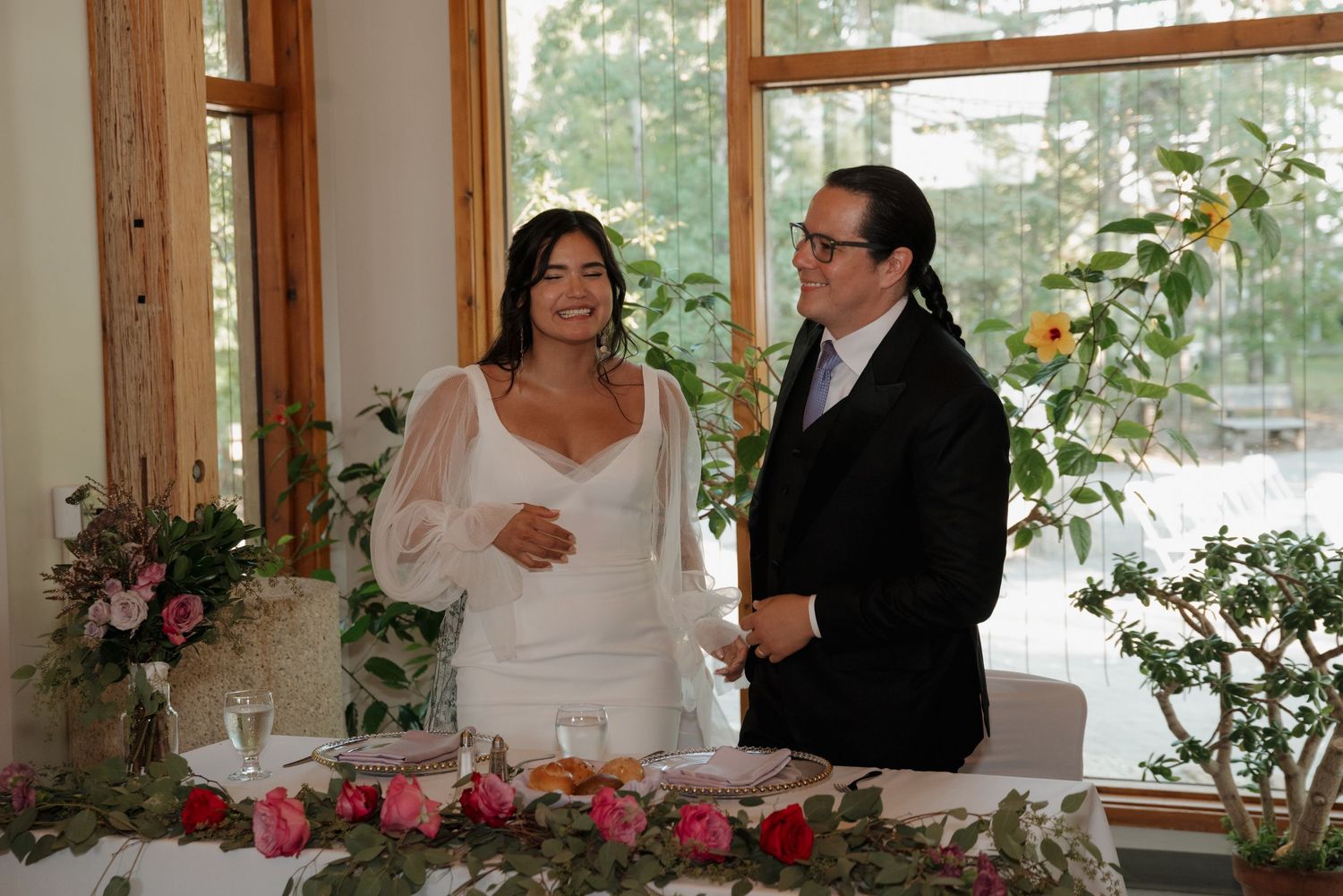 Indoor wedding venue with large windows, wooden beams, and natural lighting.