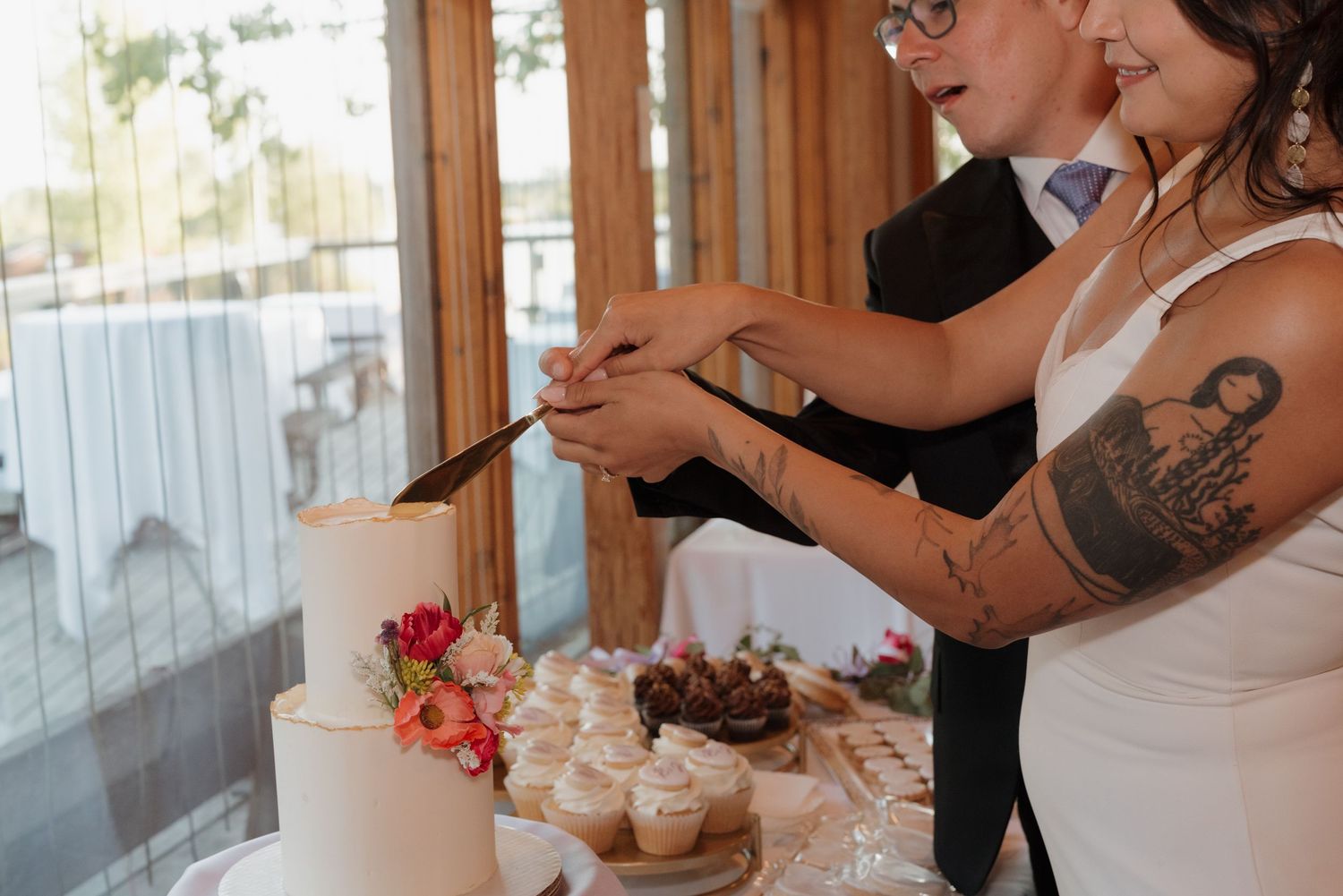 Wedding dessert table featuring decorated cupcakes and treats on elegant white and gold serving platters.