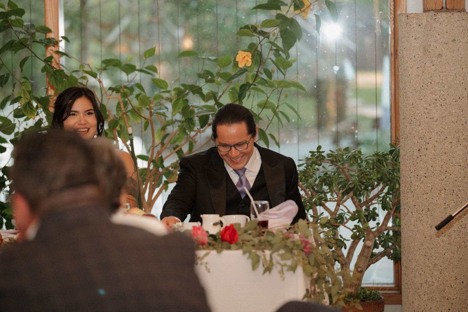 Elegant indoor wedding reception with greenery and candle decorations at dining table.