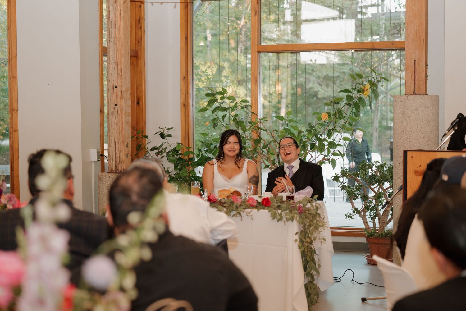 Wedding reception venue with wooden beams and large windows letting in natural light.