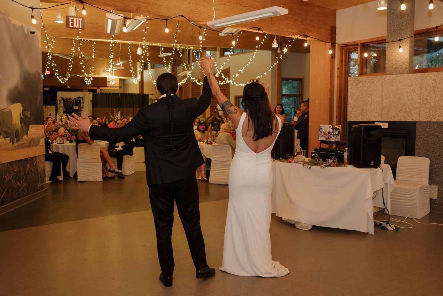 A couple dances together at an indoor wedding reception venue with warm lighting and decorative elements.