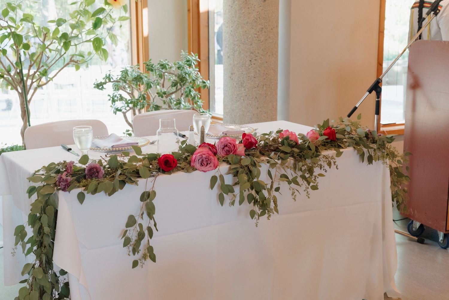 Decorative pink flowers and green vines adorn white window sills in an elegant interior hallway.
