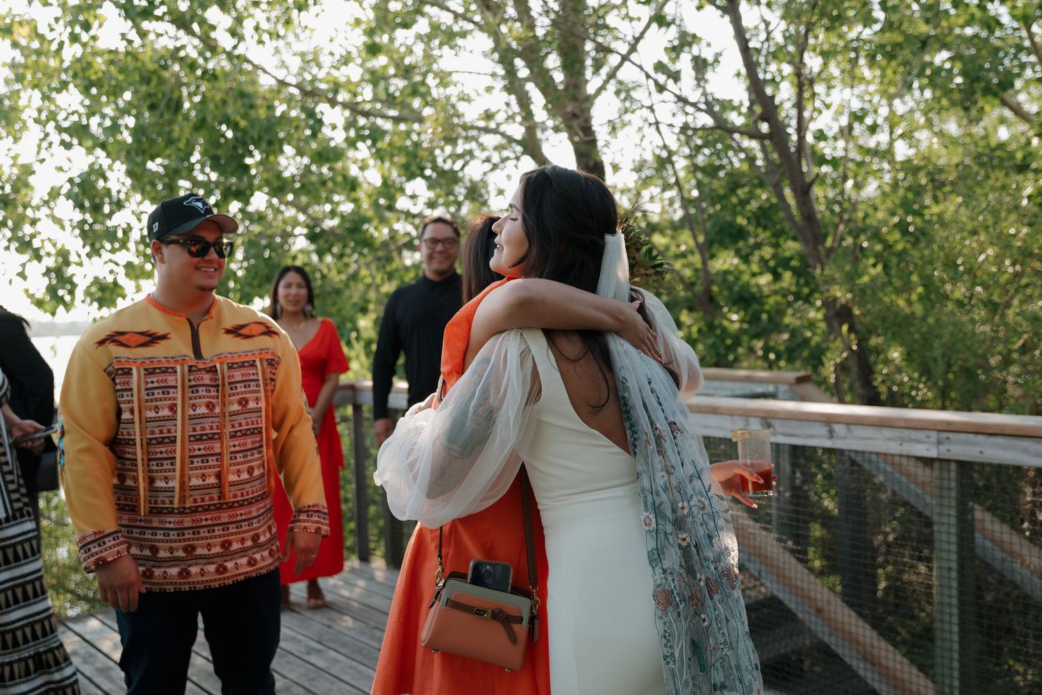 Couple shares joyful moments during outdoor wedding ceremony surrounded by greenery and natural light.