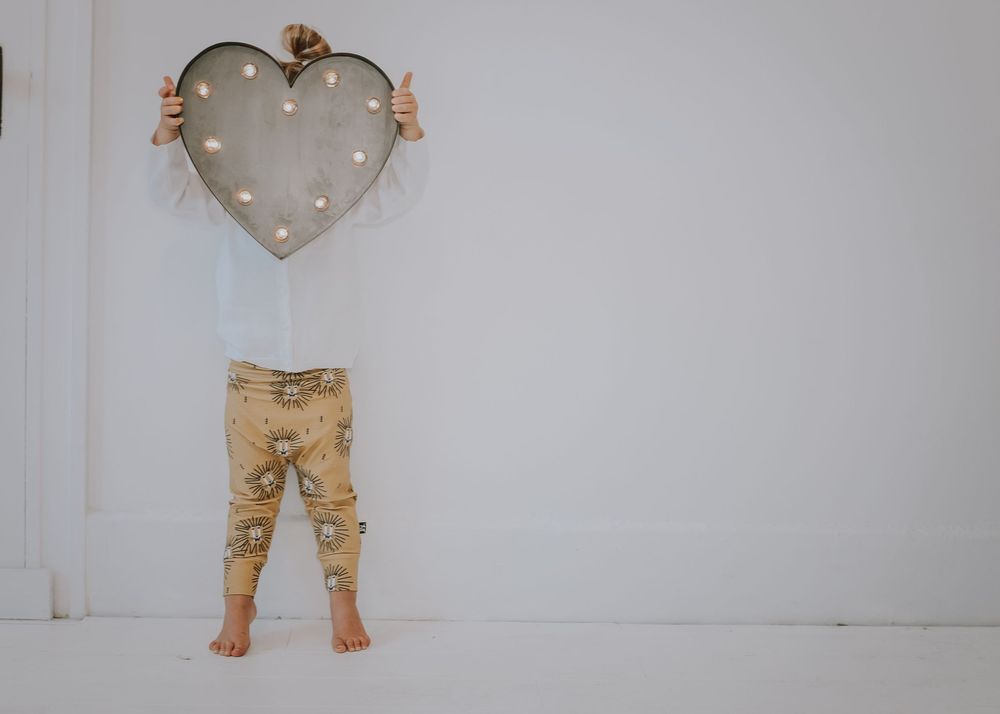 A heart-shaped wooden decor piece with rustic metal accents hangs against a light gray wall.