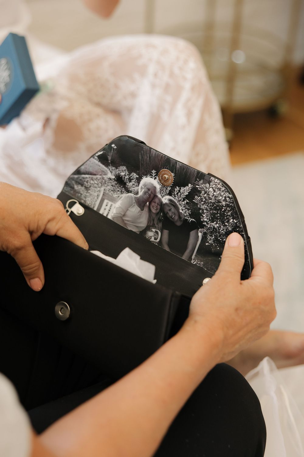 Hands carefully handling black garment bag with vintage photographs inside.