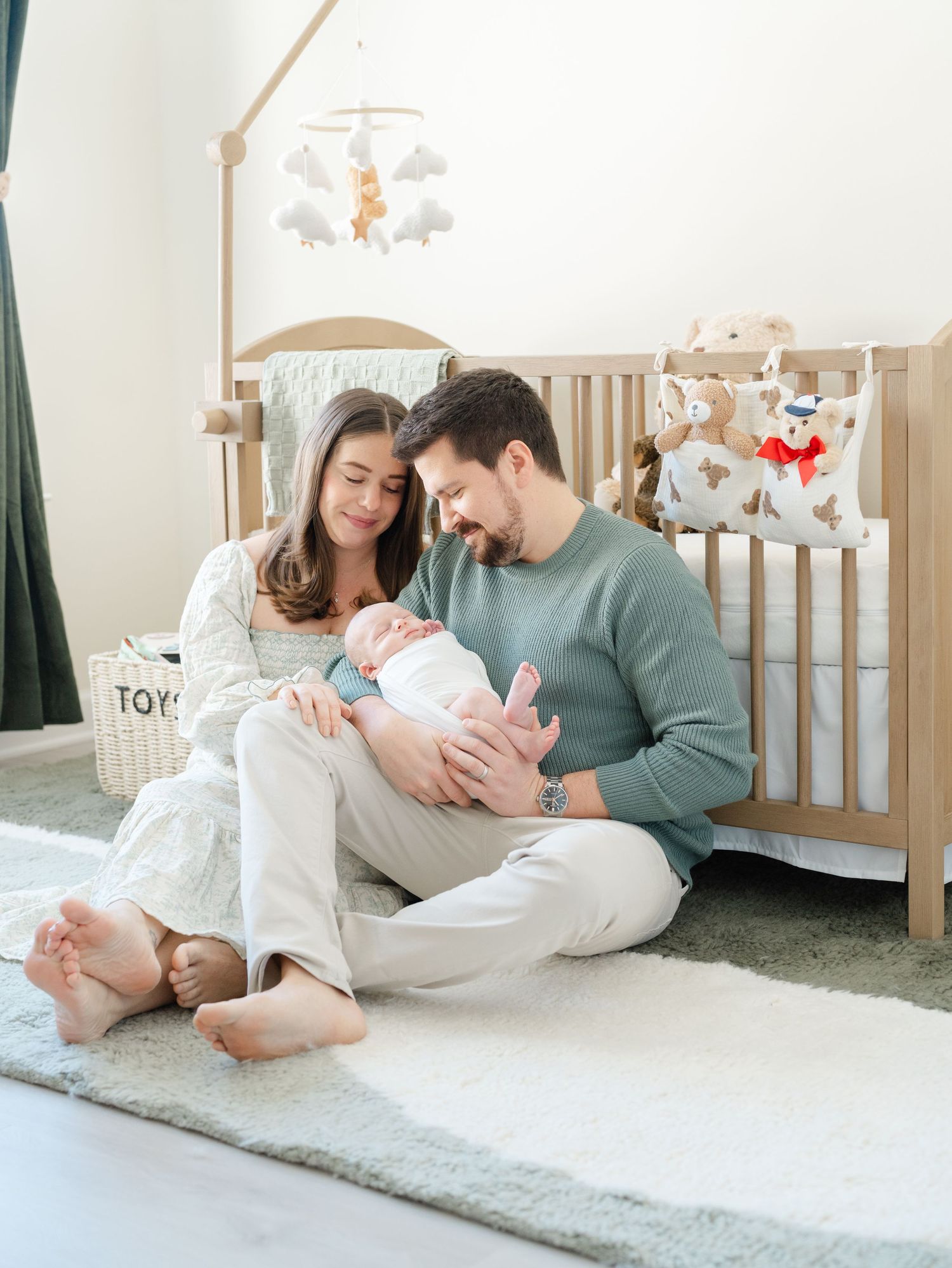 Parents cuddling newborn in nursery during lifestyle newborn photography session in Monmouth County.