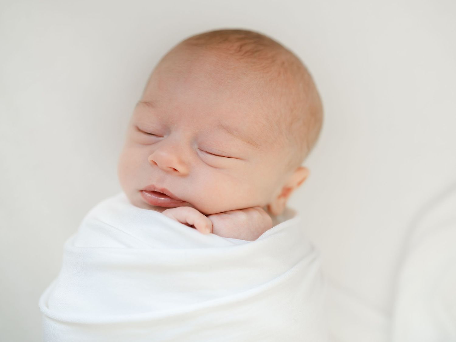 Newborn baby swaddled in white blanket, in-home newborn photography in Monmouth County