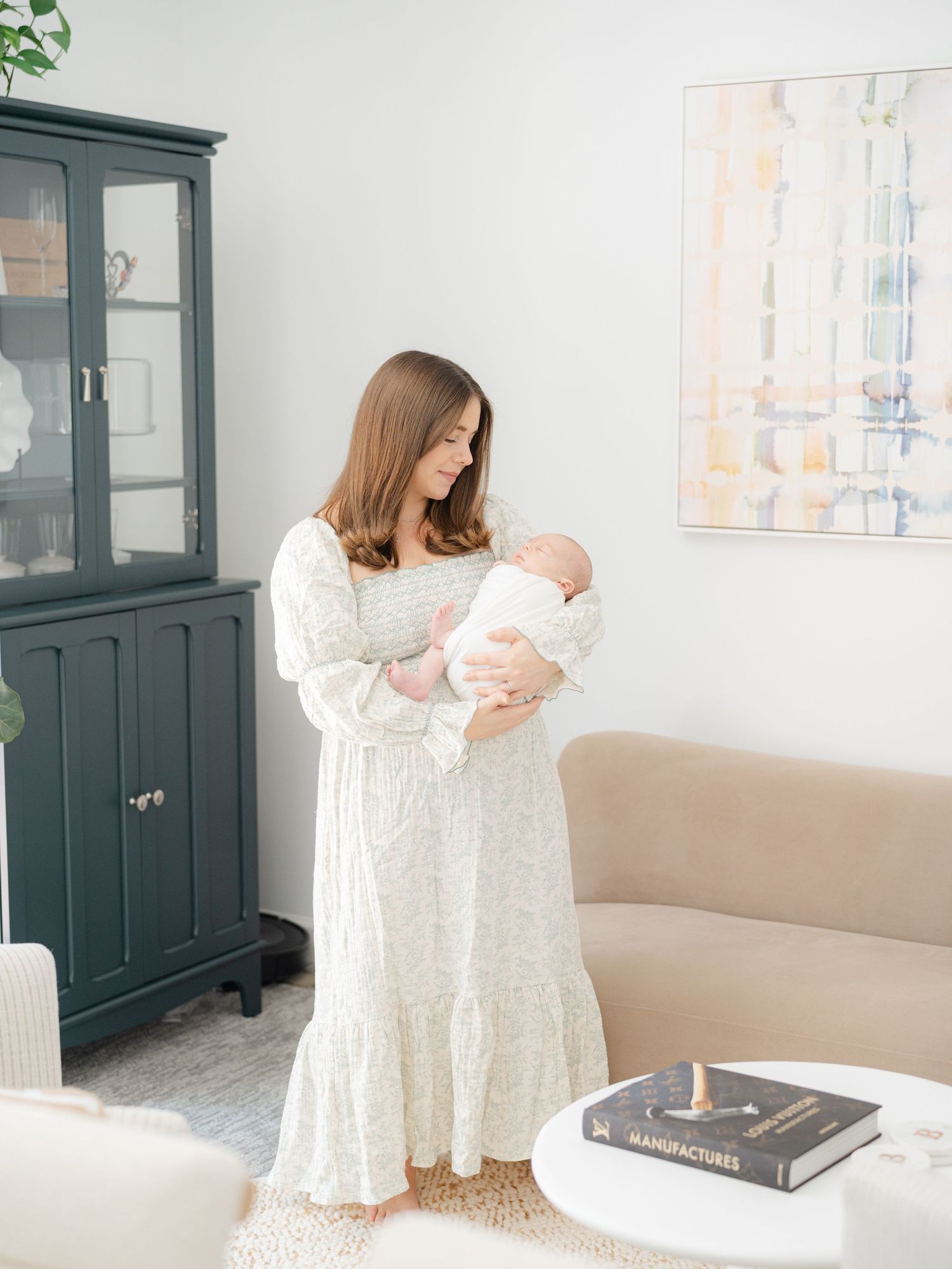 Mother holding newborn in softly lit home during in-home newborn session in Monmouth County NJ.