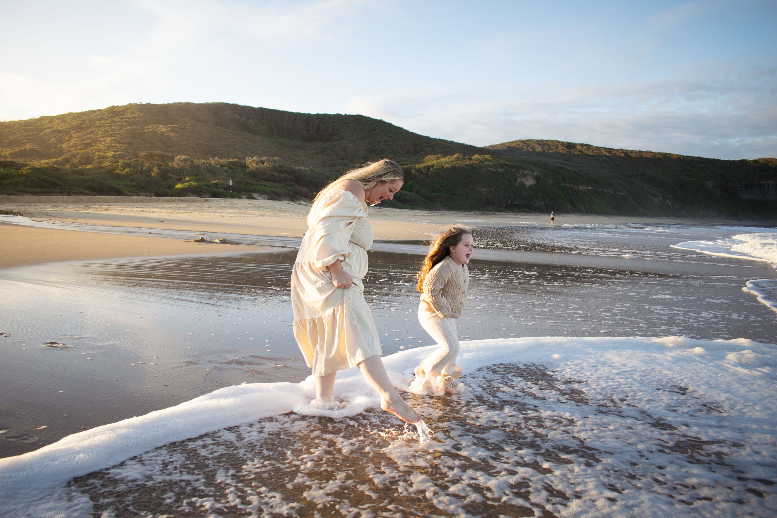 Newcastle motherhood photographer captured a mother playing with her daughter at the beach in golden hour light