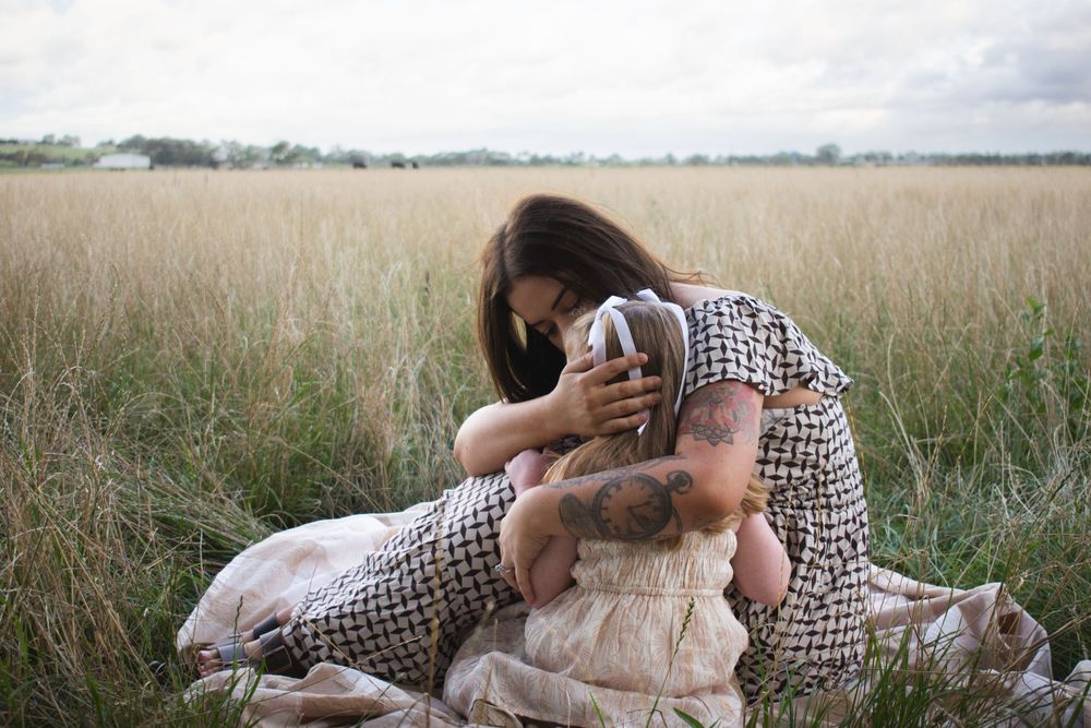 Maitland motherhood photographer capturing a mother comforting her daughter in grassy farmland