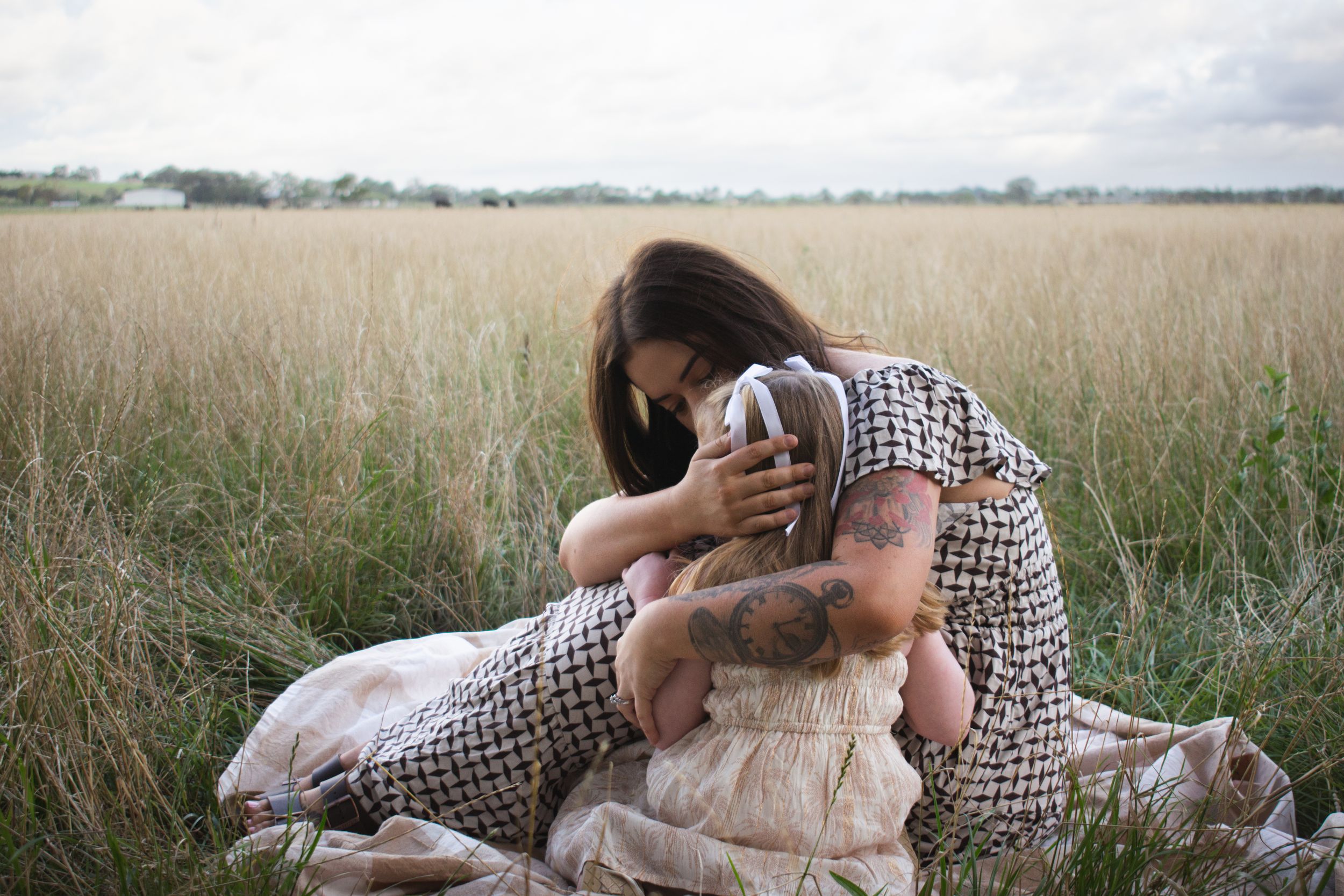 Maitland motherhood photographer capturing a mother comforting her daughter in grassy farmland