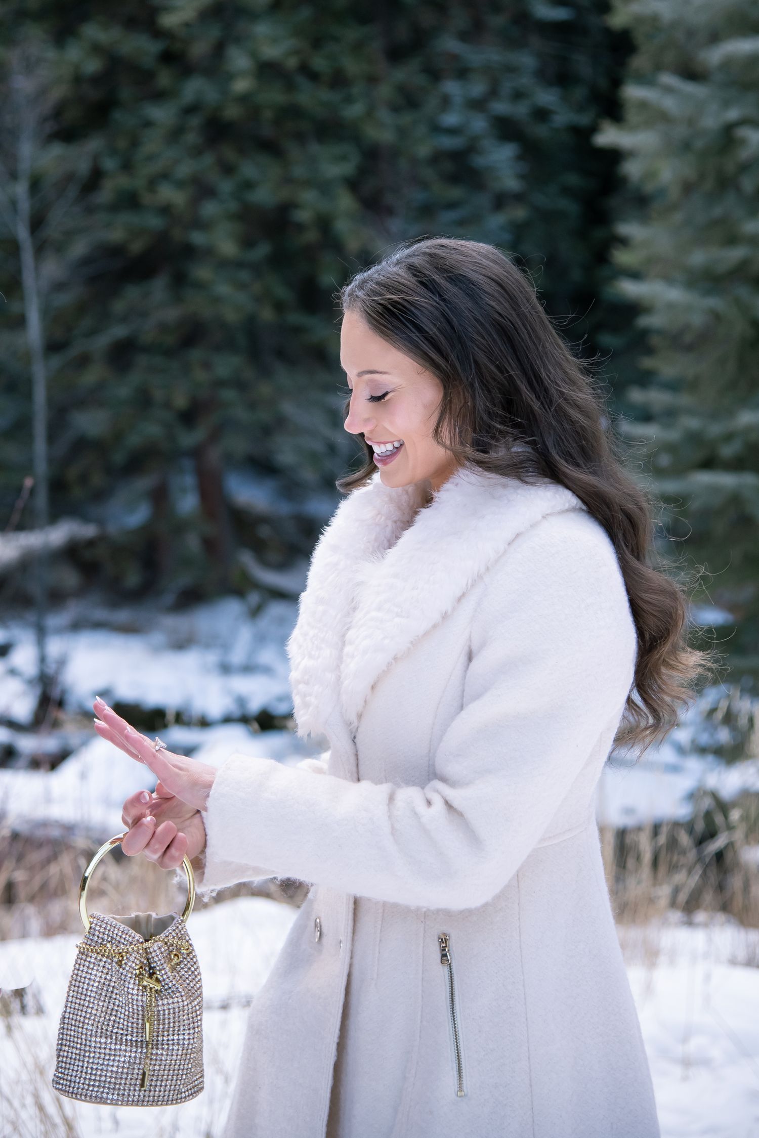 A woman smiles and gazes at her new engagement ring after a surprise winter proposal in Vail Colorado.