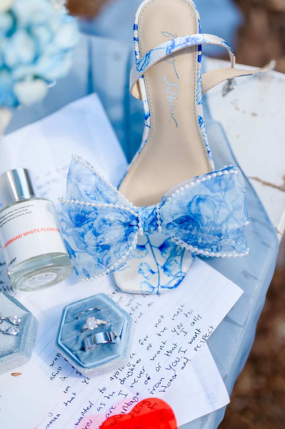 Wedding invitation cards with delicate blue ribbons and decorative details arranged on a rustic surface.