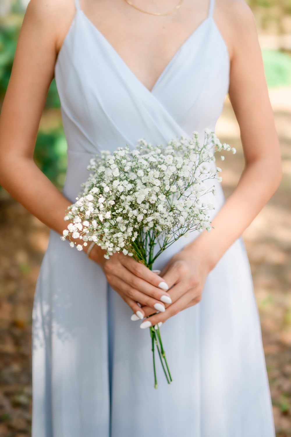 A delicate bouquet of white baby's breath flowers held against a light blue bridesmaid dress.