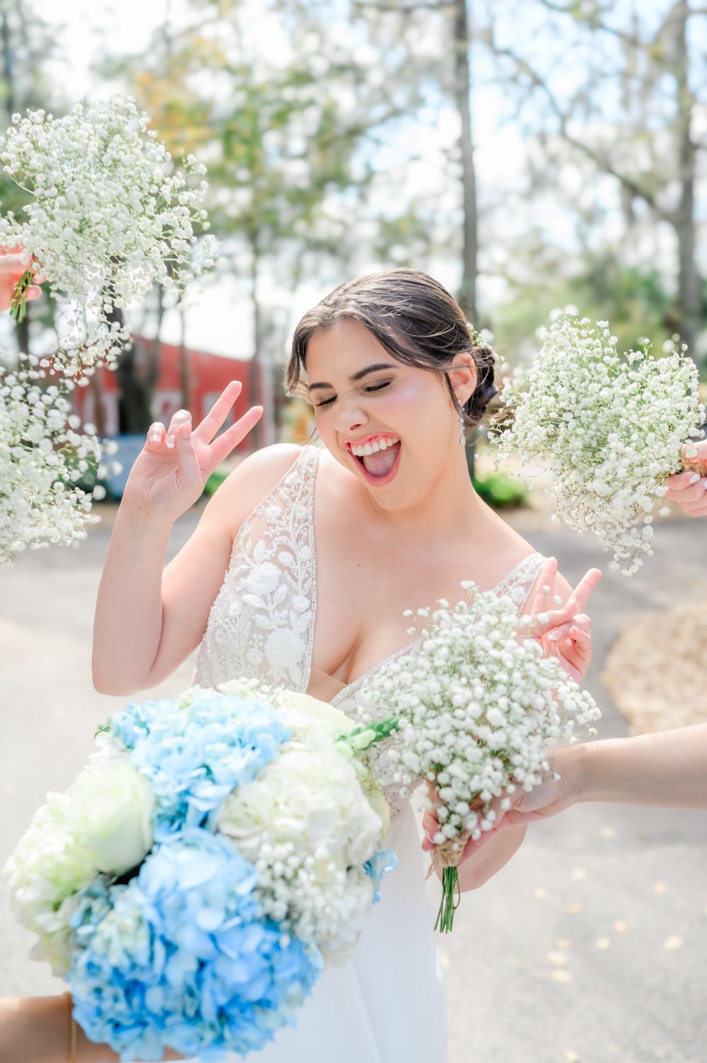 Wedding bouquet with white baby's breath and blue hydrangeas against a bright outdoor background.