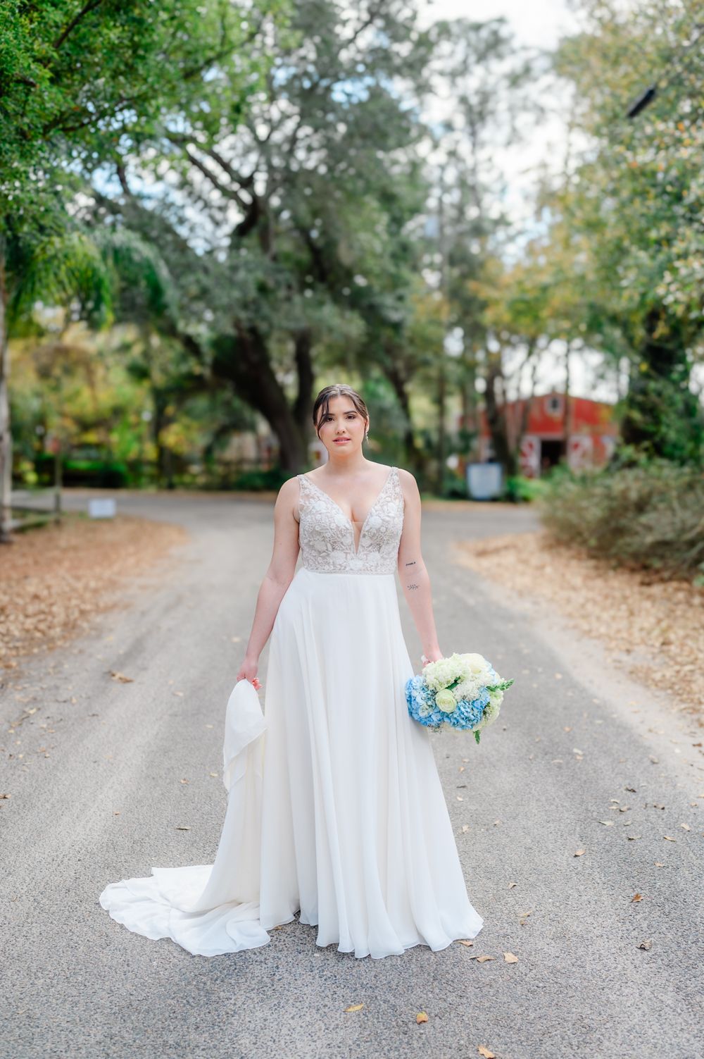 Wedding portraits on a scenic gravel path surrounded by autumn trees.