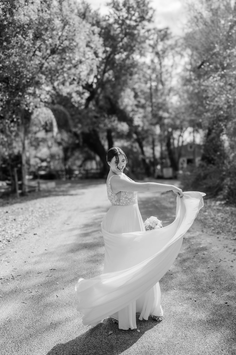 Black and white series of a flowing wedding dress twirling on a tree-lined path.